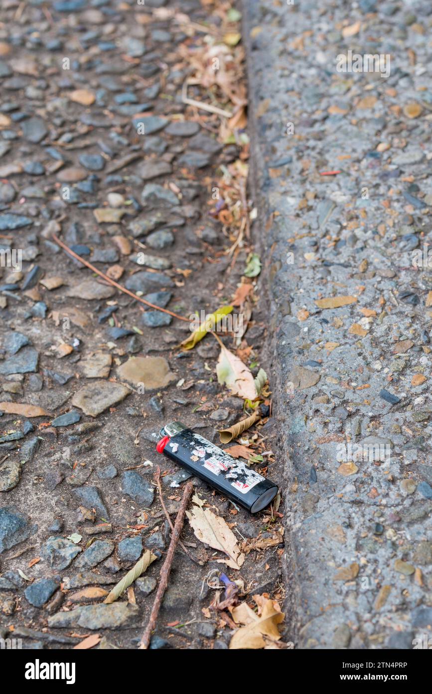 A scratched and discarded disposable cigarette lighter in a street gutter in Sydney, Australia Stock Photo