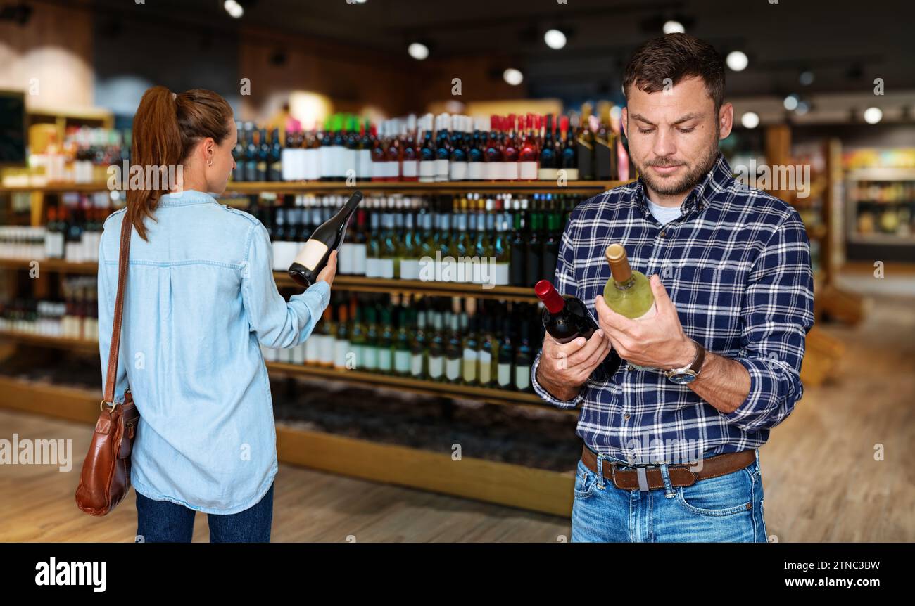 People consumers choosing wine in liquor store. Stock Photo