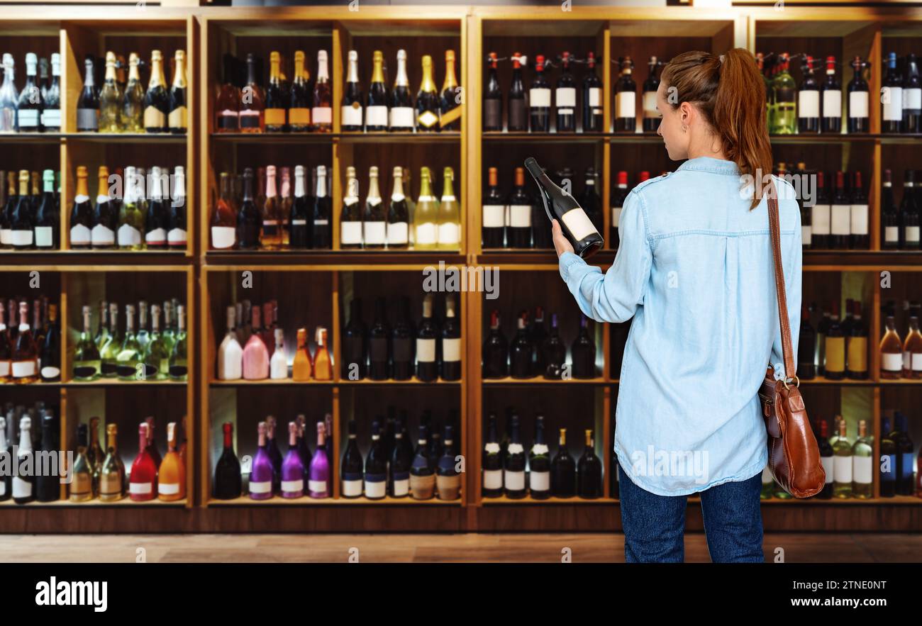 Woman consumer standing in liquor store and choosing wine. Stock Photo