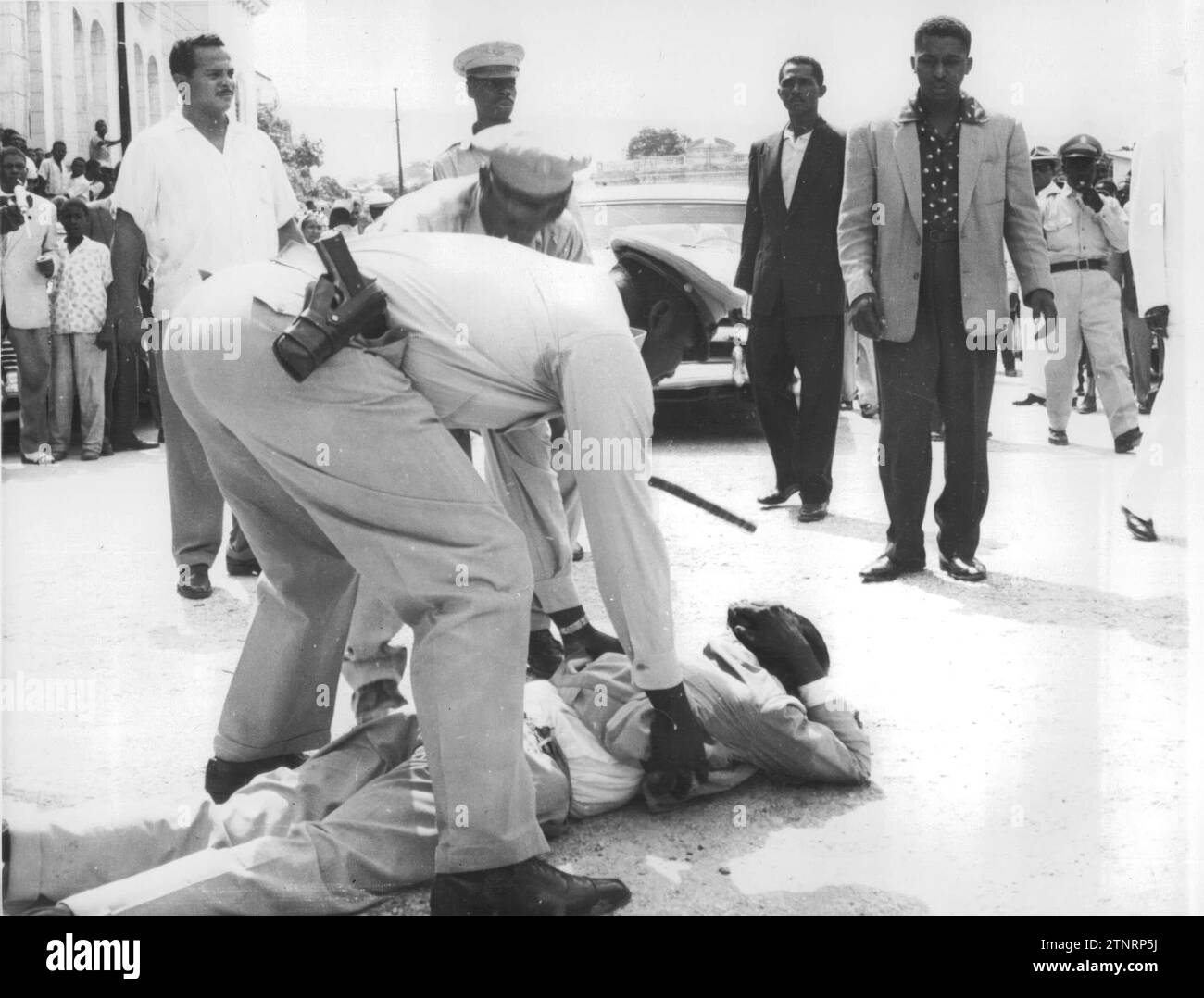 05/20/1957. A supporter of Haitian presidential candidate Francois Duvalier is pictured being searched and treated by a police officer after a rally held in Port-au-Prince. The Haitian army has had to take over the government, having imposed severe press censorship measures. The first reaction to the army's intervention has been a general strike in Port-au-Prince, which appears to have spread to the entire nation. The tension is manifest. Presidential Elections Announced for June 16. Credit: Album / Archivo ABC / Fotofiel Stock Photo