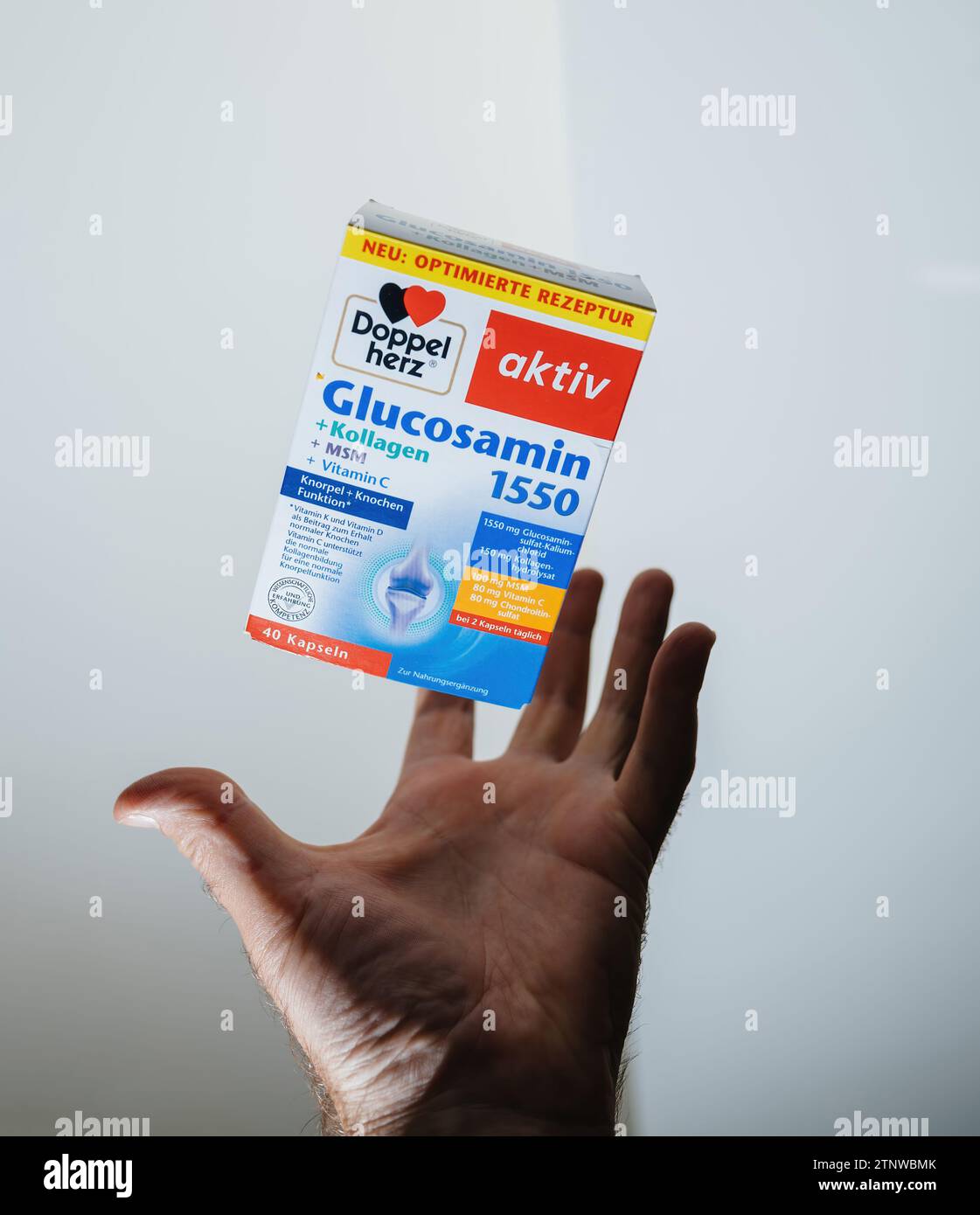 Frankfurt, Germany - Jun 12, 2023: Male hand catching flying Glucosamin 1550 by Doppel Herz, a food supplement, showcasing health and wellness Stock Photo