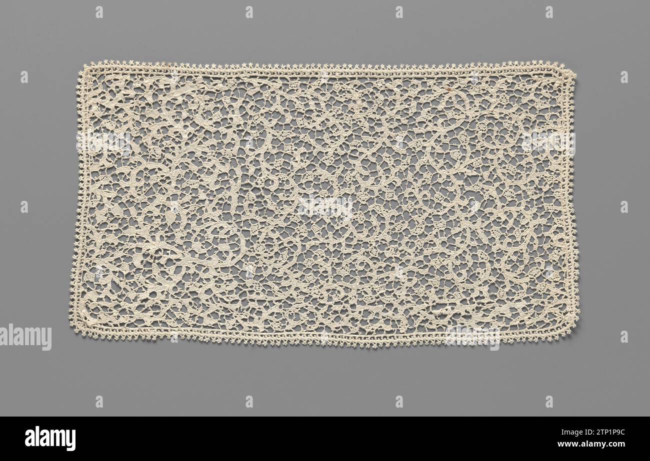 Strip of needle side with spiral vines entertained into a rug, anonymous, c. 1900 Strip of natural needle side, venise flat. The strip was entertained around 1900 into a rug. Pattern with irregular branched spiral vines, on which coral -shaped buds or flowers and short -length leaves. Soil with irregularly potented bars. Motives with highly closed feston or buttonhol stitches, without relief and with little decorative stitches. The rug is put together with many pieces. For example, there are narrow strips along three sides with another pattern, across the spiral vines. All around it is finishe Stock Photo