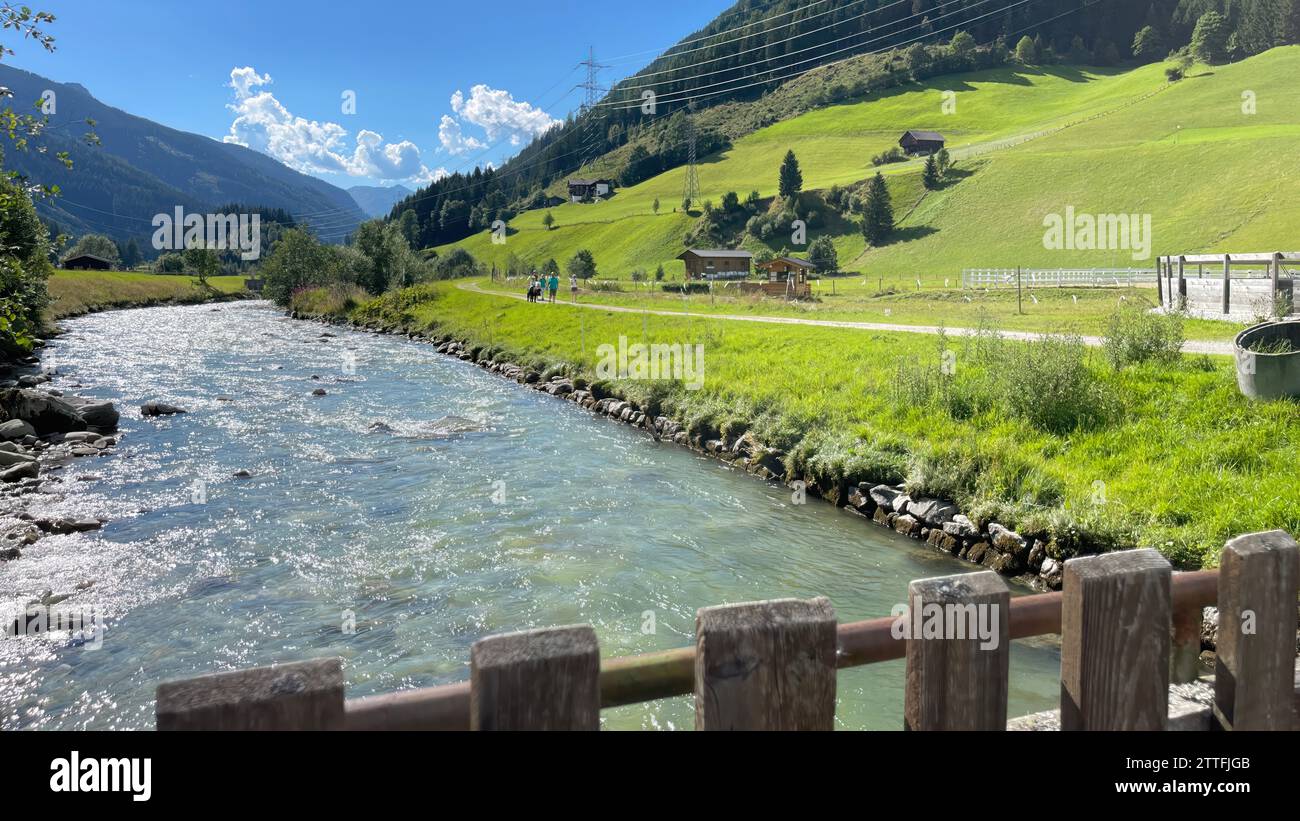 Alpine river with hikers in lush valley Stock Photo - Alamy