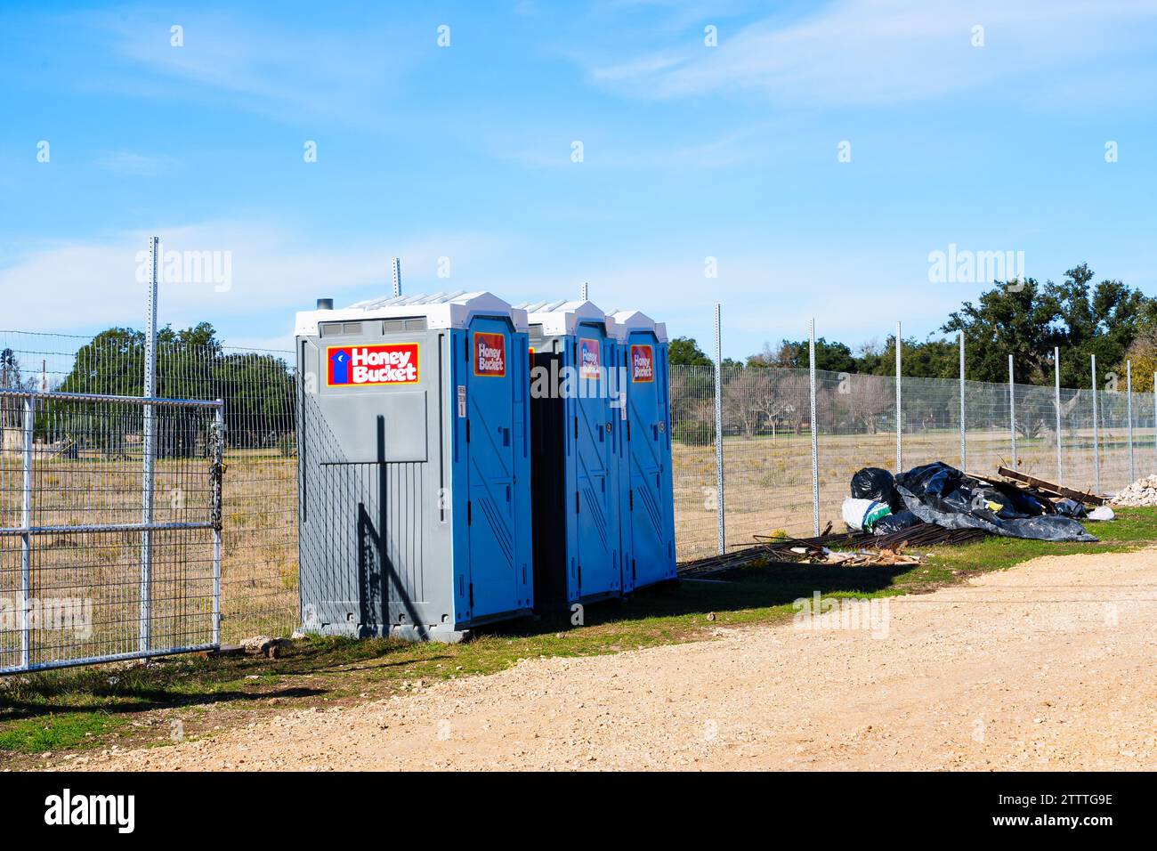 Three portable toilets or porta-pottys lined up at a construction site. Stock Photo