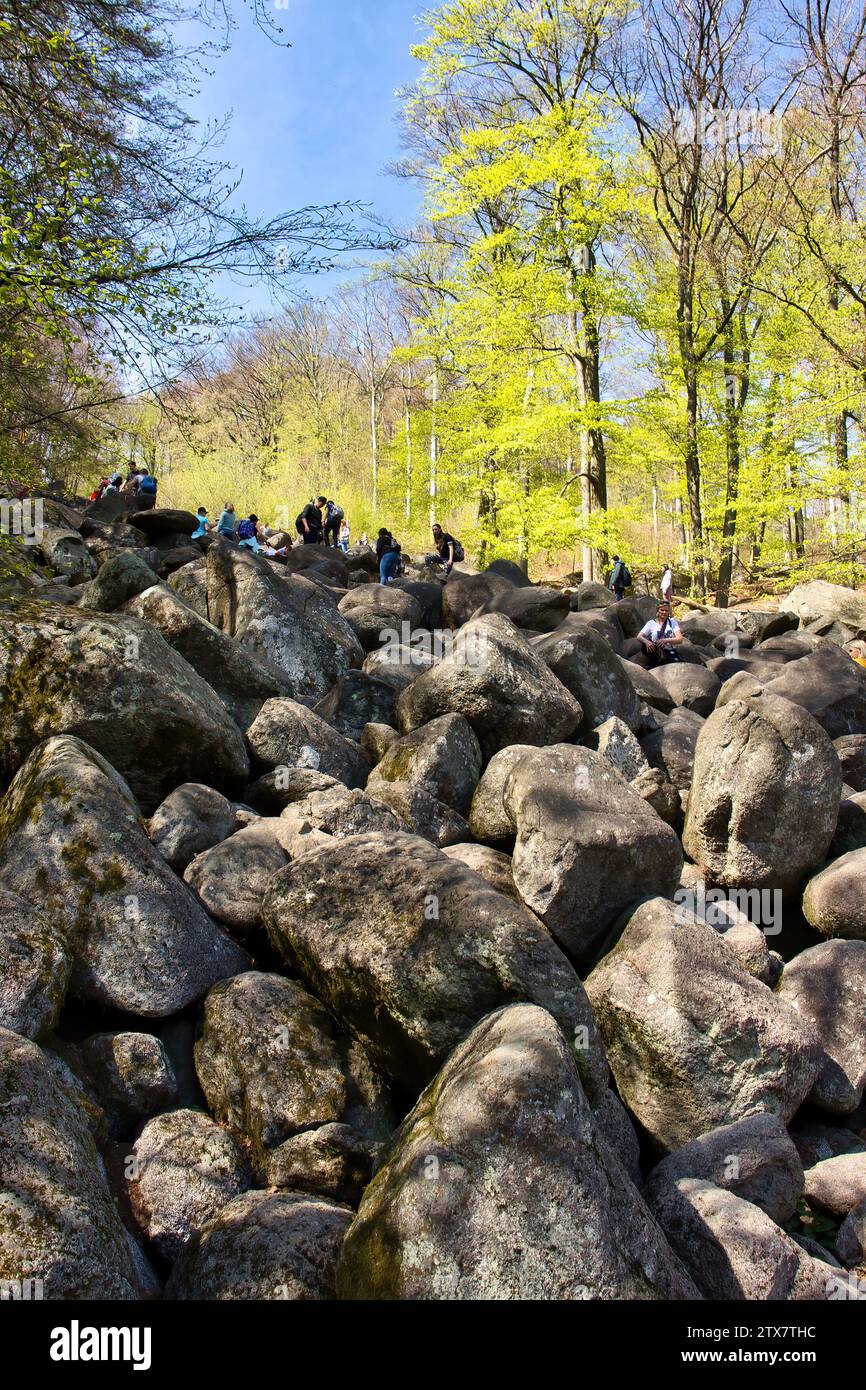 Lautertal, Germany - April 24, 2021: People at the top of a hill covered in large rocks on a spring day at Felsenmeer in Germany. Stock Photo