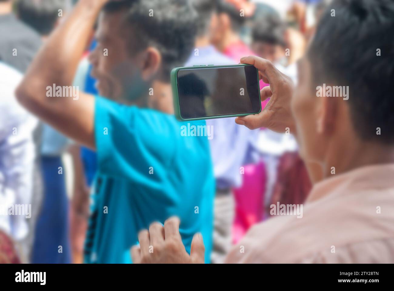 Man holding smart phone mobile shooting burmese people dress in national costumes, Come out to participate and dance in the Kathin festival during the Stock Photo