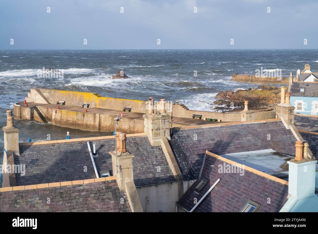 Findochty Harbour and house roof tops along the coast with a turbulent sea. Findochty, Morayshire, Scotland Stock Photo