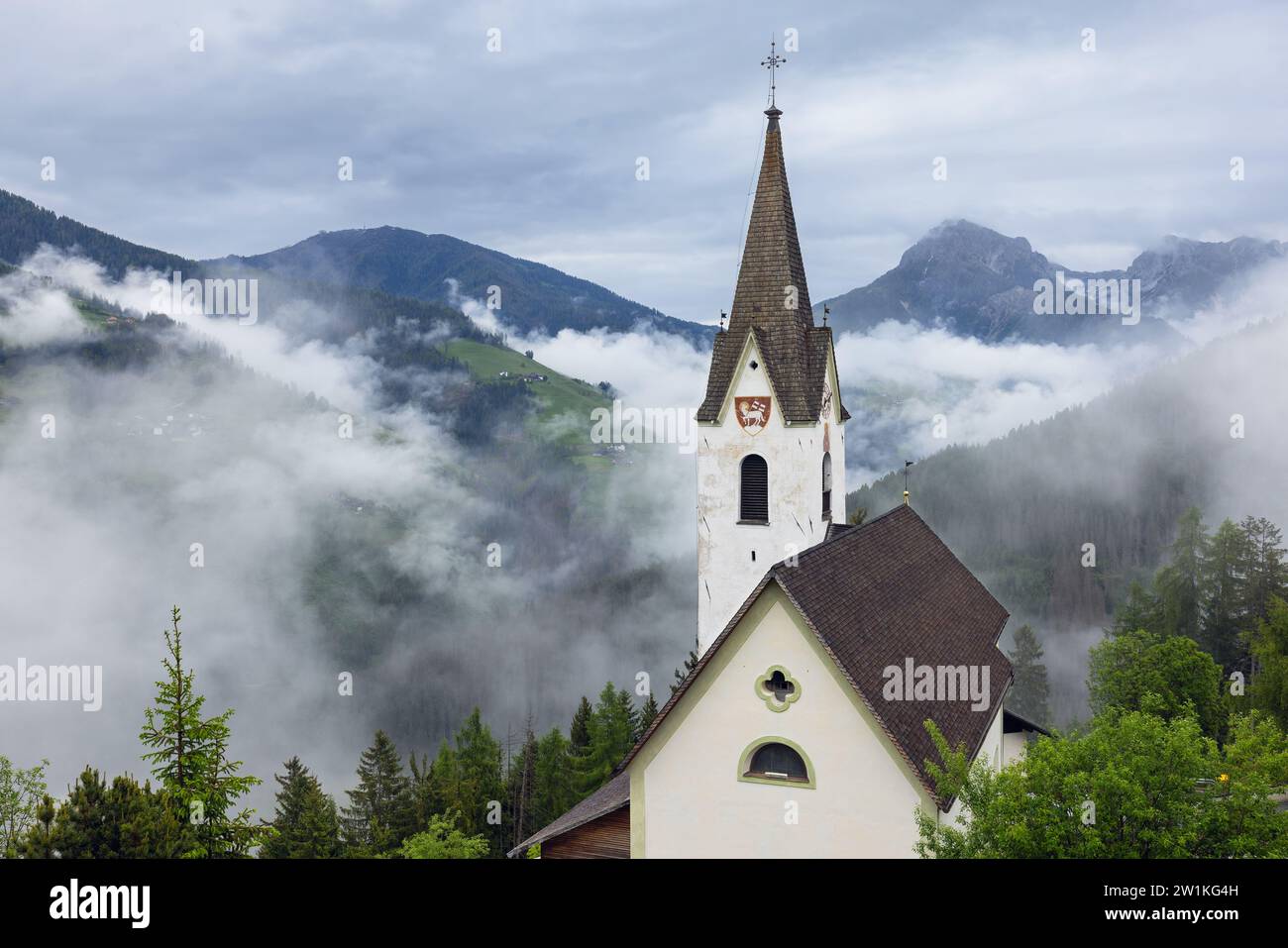 Church on the background of the Italian Alps in the morning clouds Stock Photo