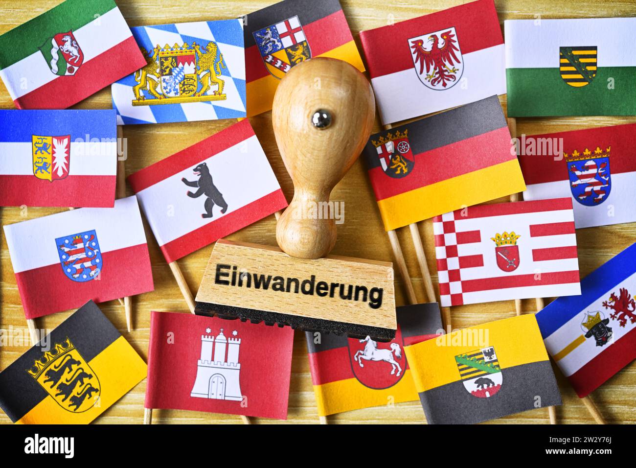 FOTOMONTAGE, Stempel mit Aufschrift Einwanderung inmitten Fahnen der deutschen Bundesländer Stock Photo