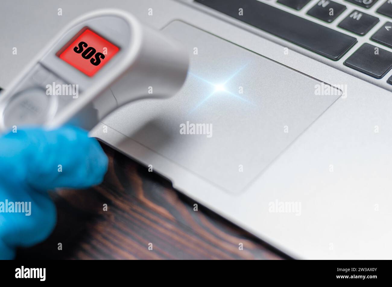 The technician applies an infrared thermometer to the laptop panel