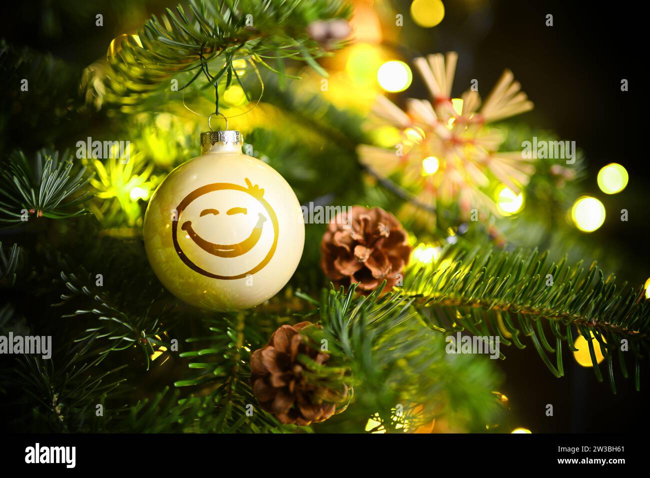 FOTOMONTAGE, Weihnachtskugel mit Smiley hängt an einem Weihnachtsbaum Stock Photo
