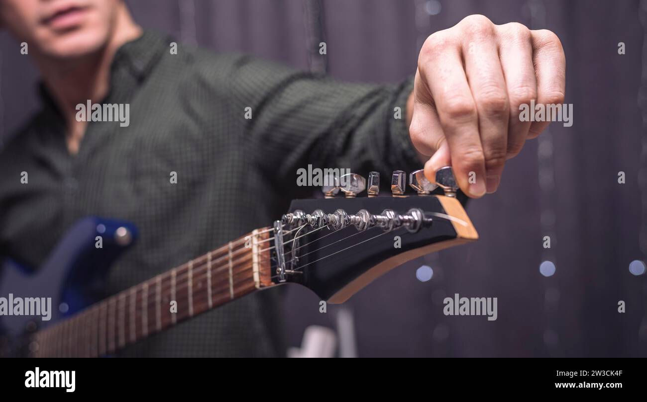Image of a musician tuning a guitar. Concerts concept. Mixed media Stock Photo
