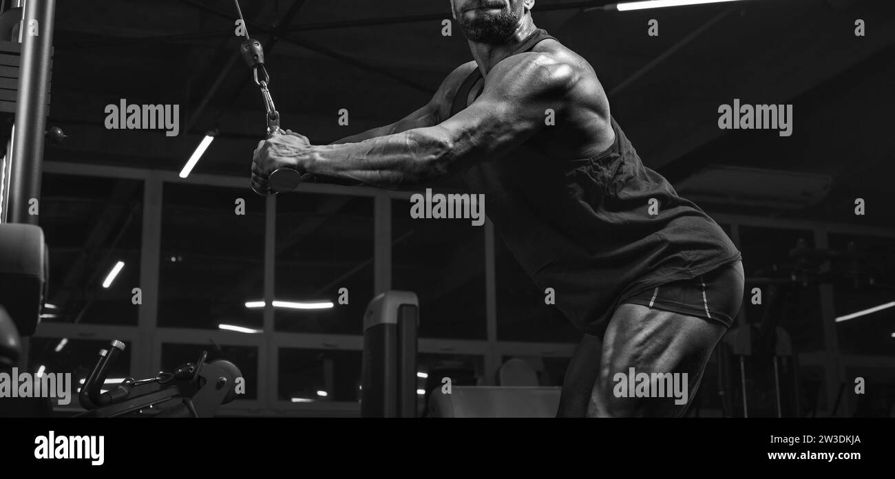 Image of a powerful athlete exercising in a crossover at the gym. Triceps pumping. Fitness and bodybuilding concept Stock Photo