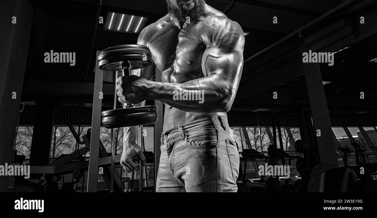 Professional athlete trains with a dumbbell in the gym. Bicep pumping