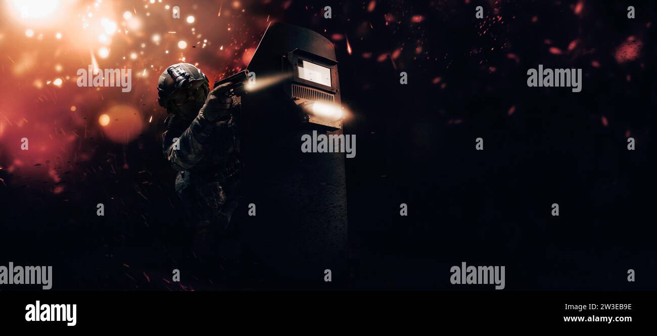 Portrait of a fighter of a special unit. He hides behind a bulletproof shield. Background of war. The concept of the fight against terrorism. Mixed Stock Photo