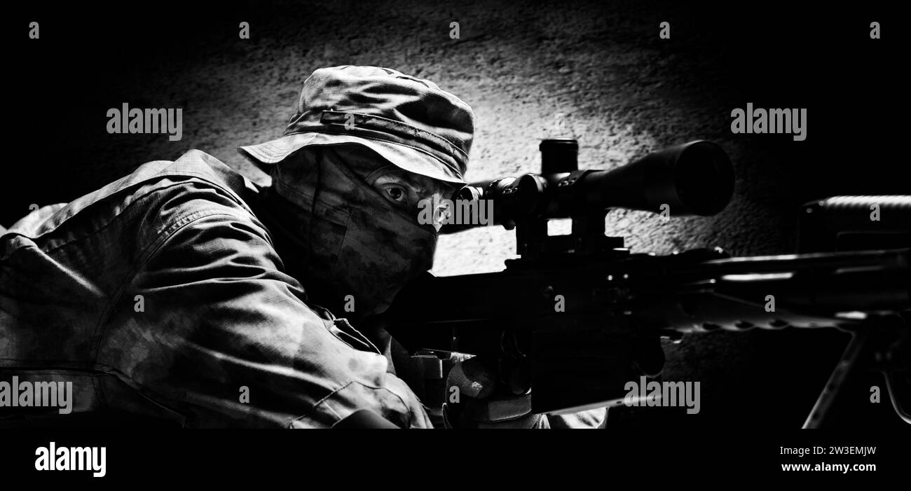 The sniper lies and aims through the telescopic sight. Mixed media Stock Photo