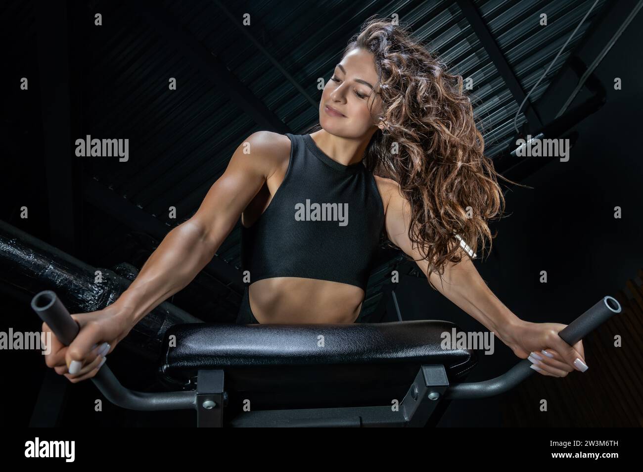 Charming brunette doing hyperextension in the gym. Press pumping. Fitness and bodybuilding concept. Mixed media Stock Photo