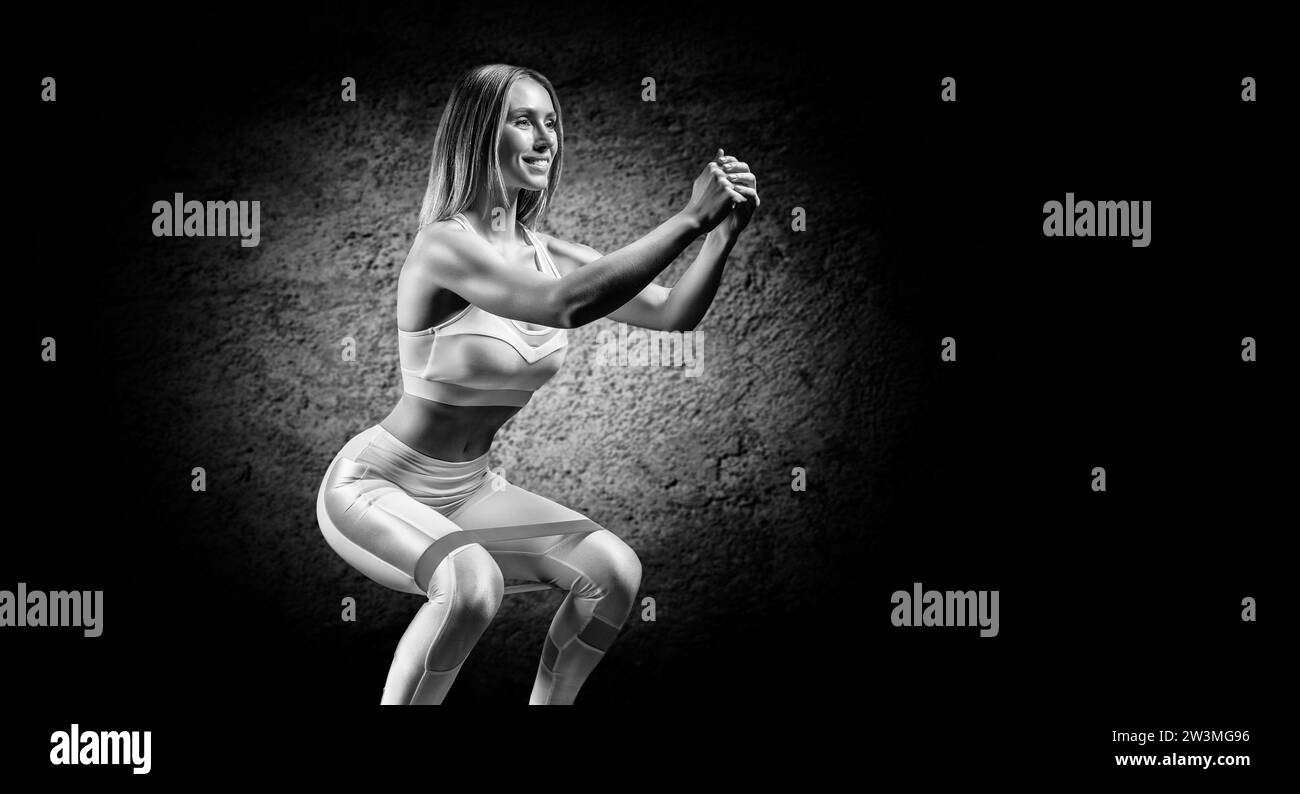 Charming girl is training in the gym with a rubber band. The concept of bodybuilding, fitness, healthy lifestyle. Light spot. Mixed media Stock Photo