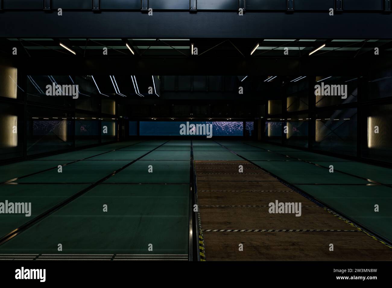 Geneva-champel station, featuring an unexpectedly wood plank over a missing floor panel, devoid of crowd. Digital display of a swimmer in the water. Stock Photo