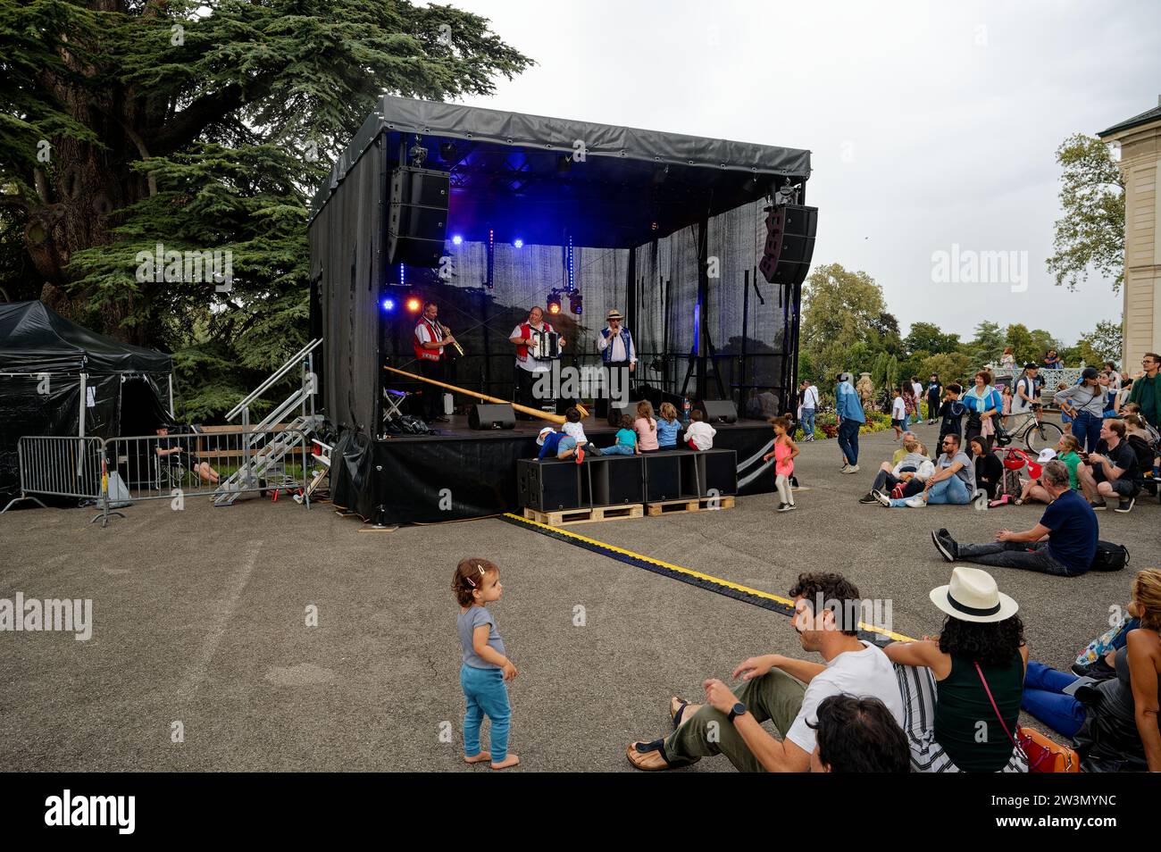 Supportive dad guides his daughter to join peers enjoying traditional Swiss melodies at La Grange Park's Swiss Day celebration. Stock Photo