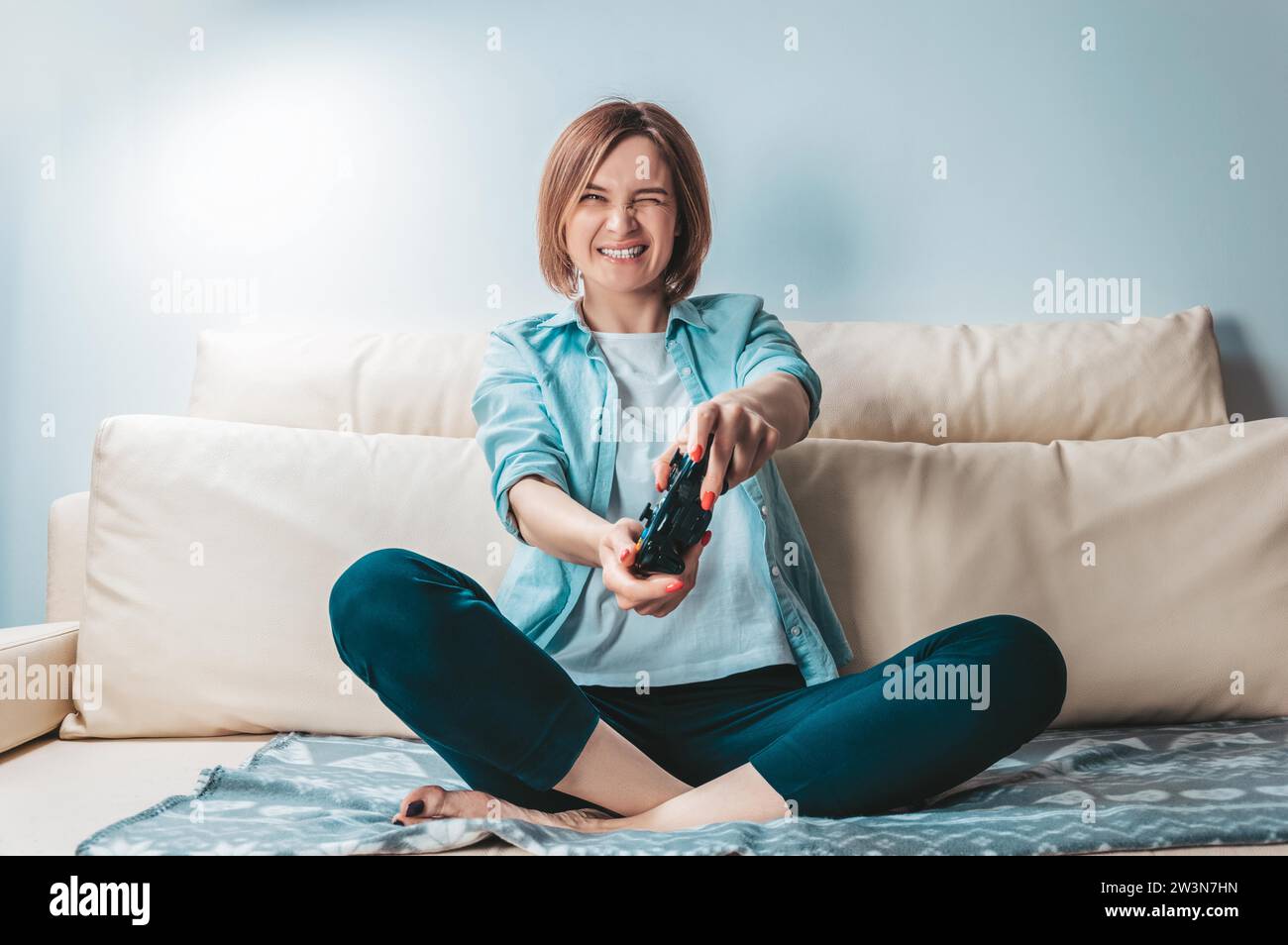 Girl with a joystick in her hands enthusiastically plays a computer game. ESports concept. Mixed media Stock Photo