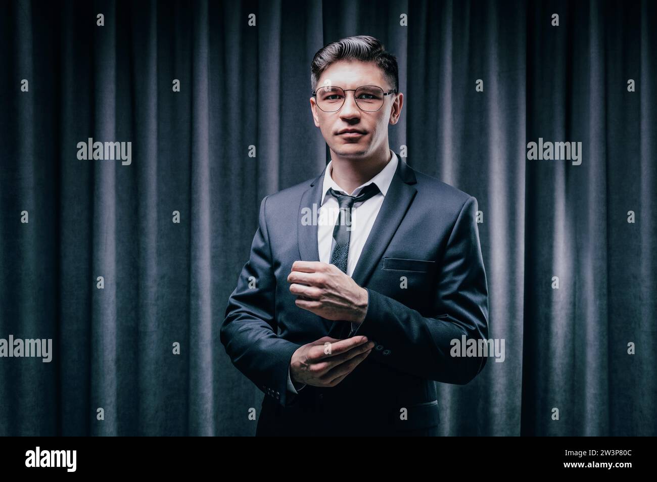 Adult man is standing in a suit against a black curtain. Business concept. The administrative staff of the company. Mixed media Stock Photo