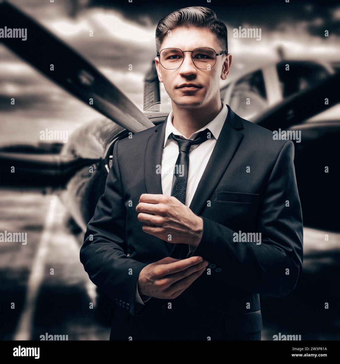 Portrait of a man in a business suit. He stands at the airport amid a sports plane. Aircraft Designer. Private airlines. Mixed media Stock Photo