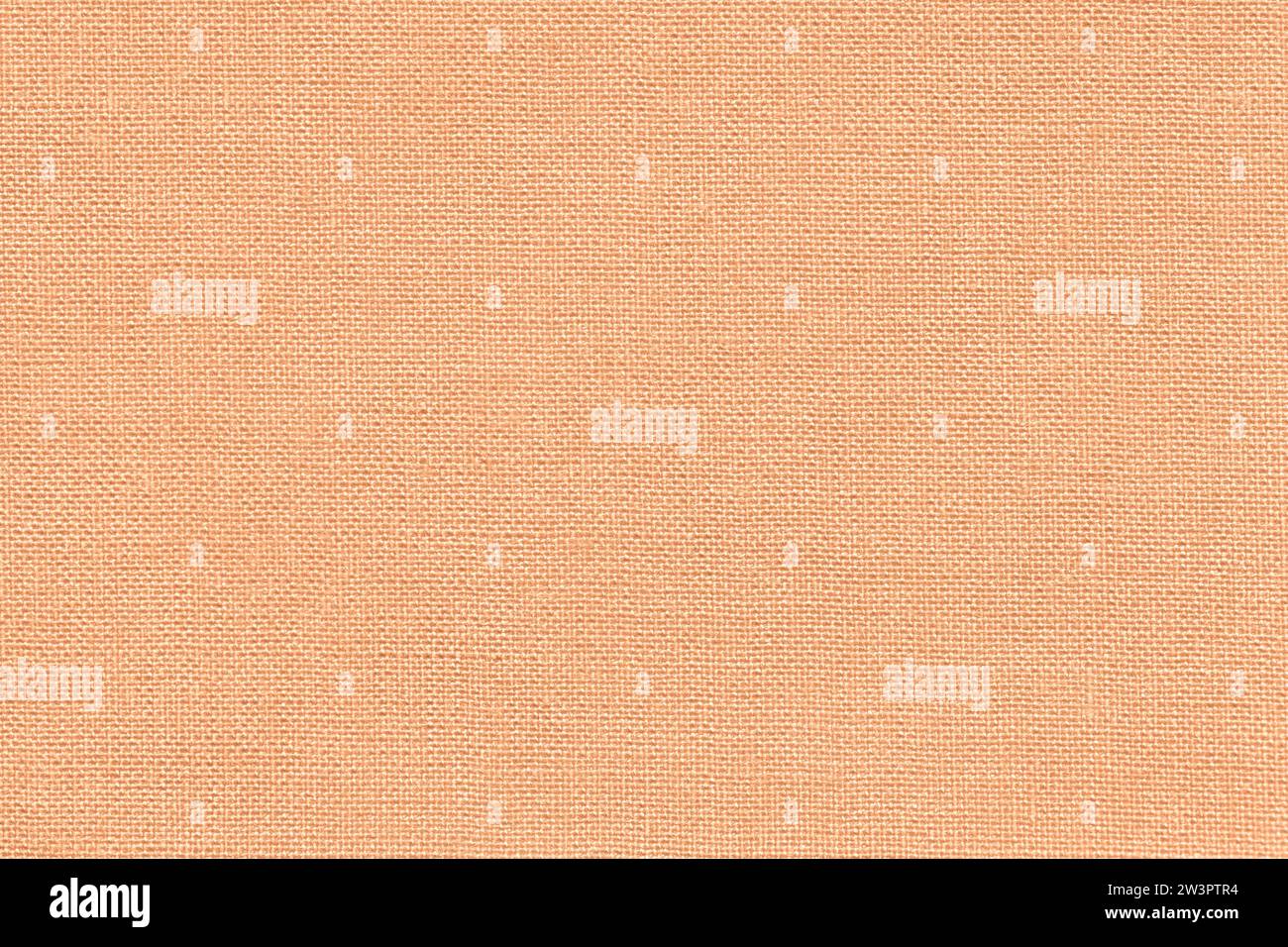 Color of the year 2024 peach fuzz. Light coral background from textile material with wicker pattern, closeup. Structure of the fabric with natural tex Stock Photo