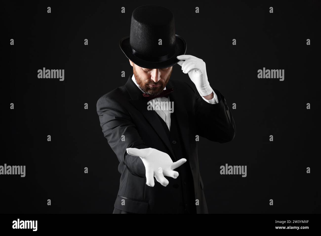 Magician in top hat on black background Stock Photo - Alamy