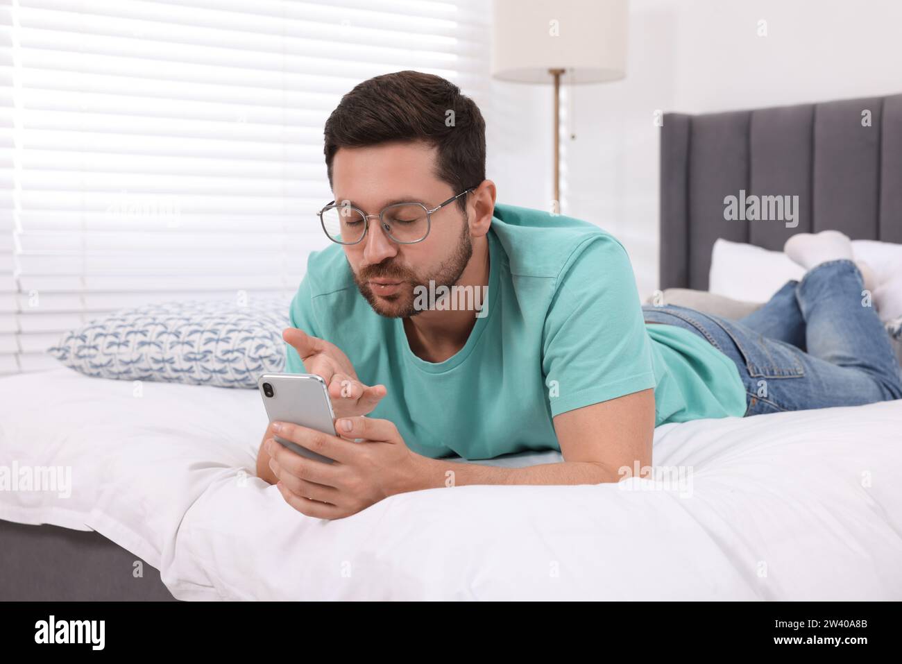 Man blowing kiss during video chat via smartphone in bedroom. Long-distance  relationship Stock Photo - Alamy