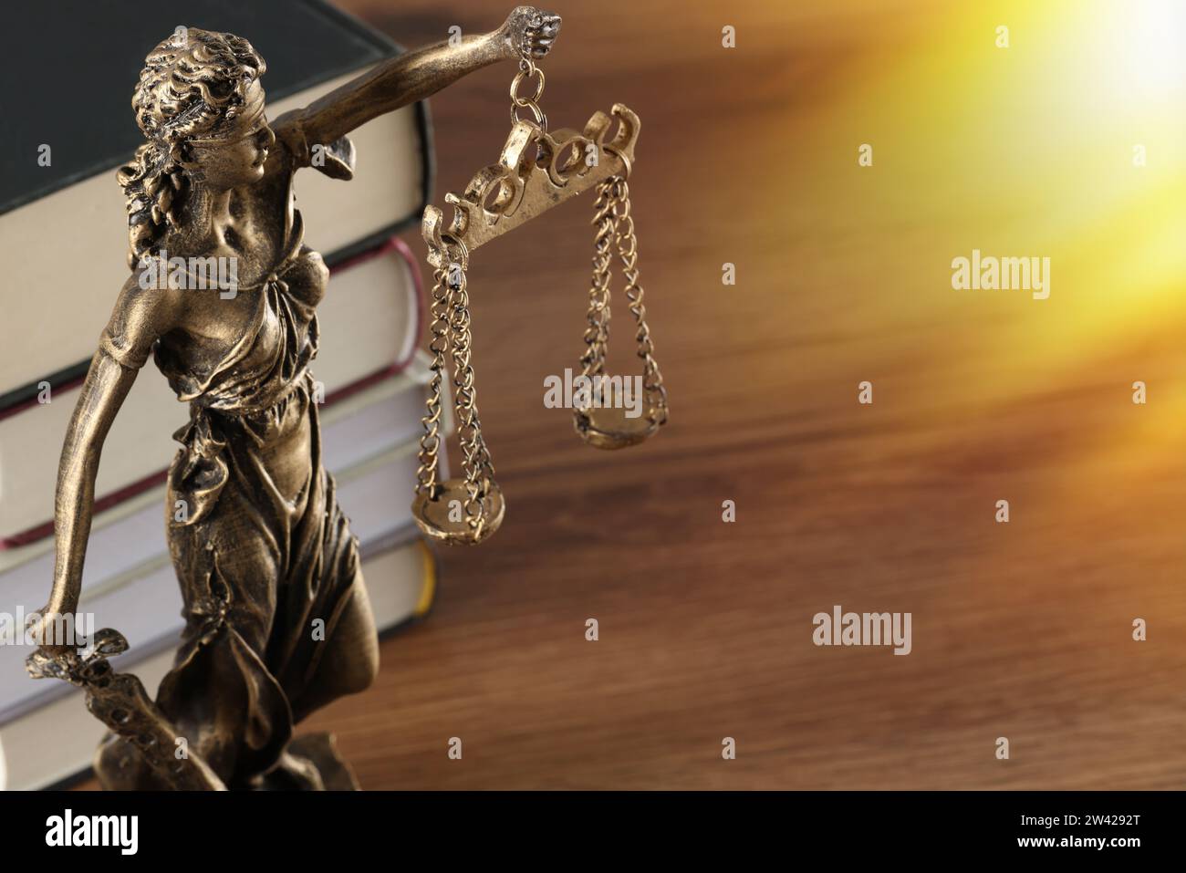 Symbol of fair treatment under law. Statue of Lady Justice and books on wooden table, space for text Stock Photo