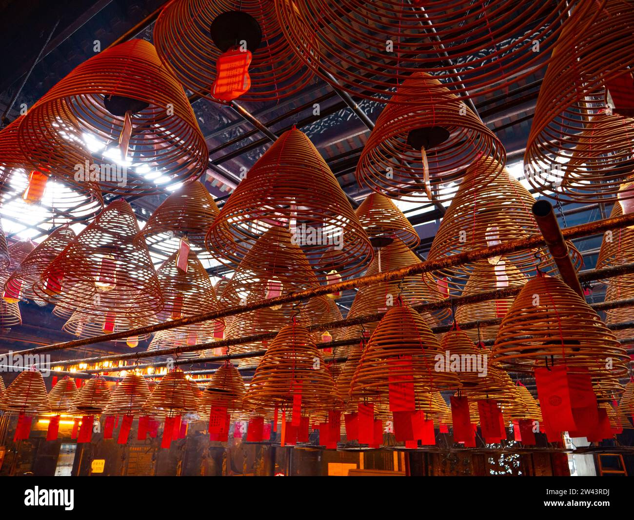 November 14, 2023. Man Mo Temple - Central area, Hong Kong. Many circle incenses are hanging on the roof inside the temple with prayer tags on them Stock Photo