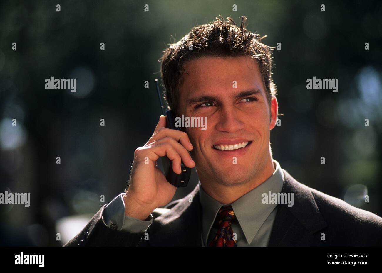 Geschäftsmann telefoniert im Park mit dem Handy Stock Photo - Alamy