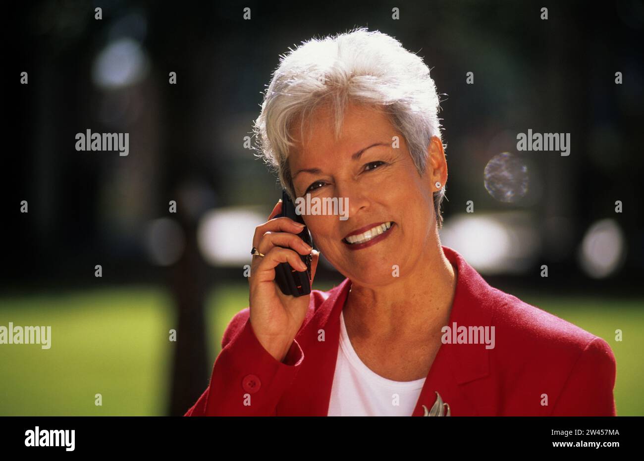 Geschäftsfrau telefoniert im Park mit dem Handy Stock Photo