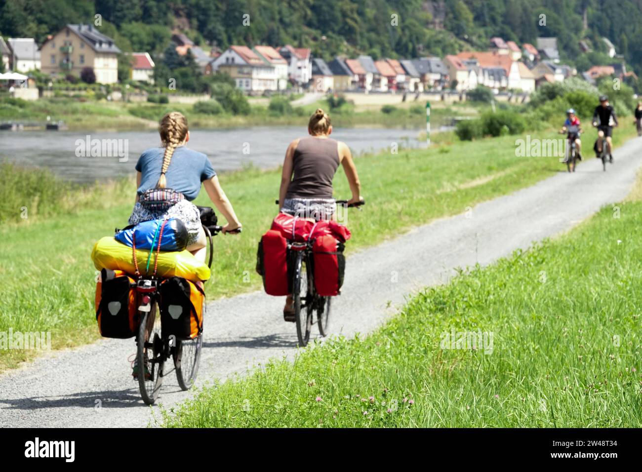 Women ride bicycles on the pathway of the Elbe River Valley Saxony Germany vacation in July People Young adults on holiday Stock Photo