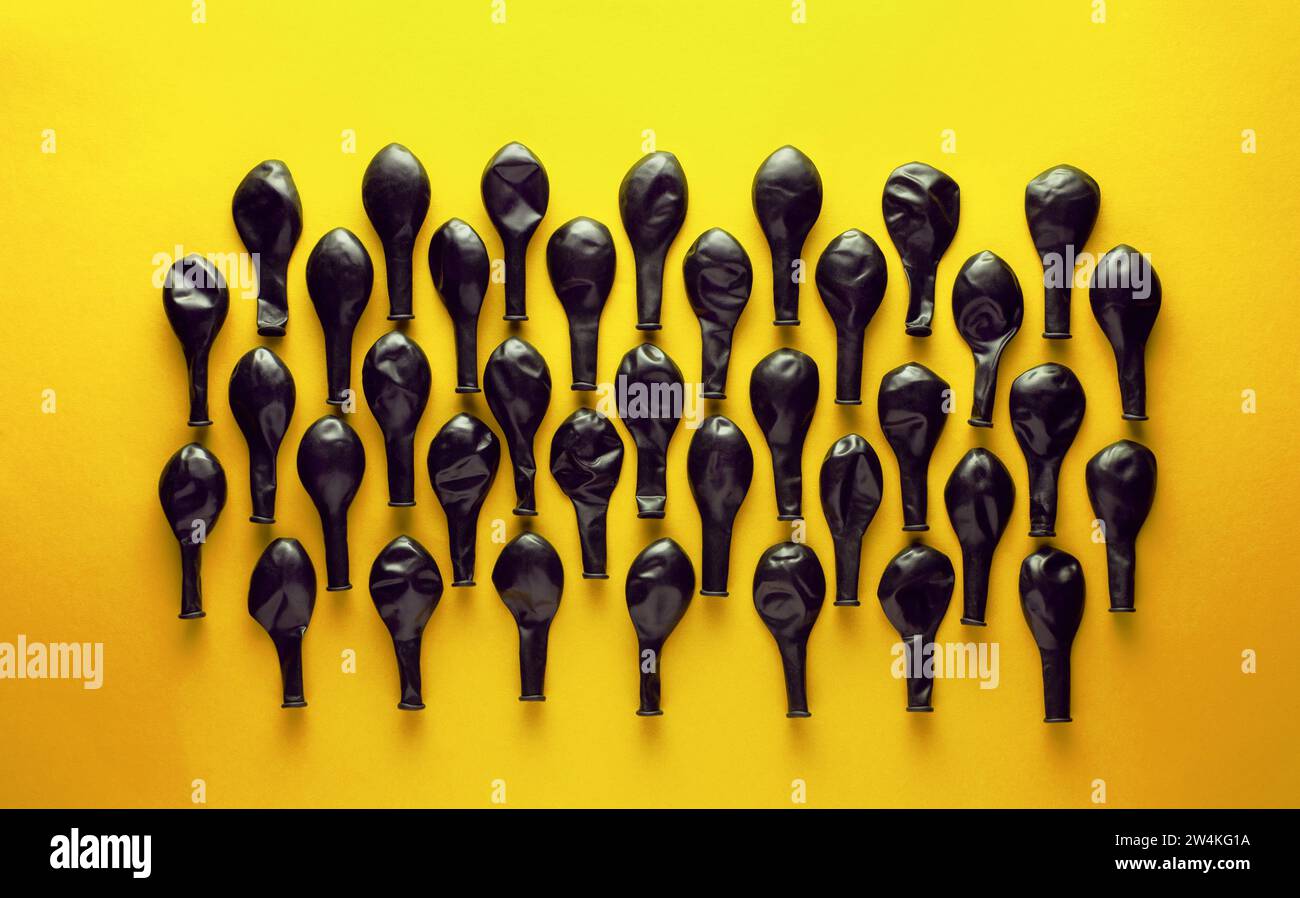 Black deflated balloons on yellow background Stock Photo - Alamy