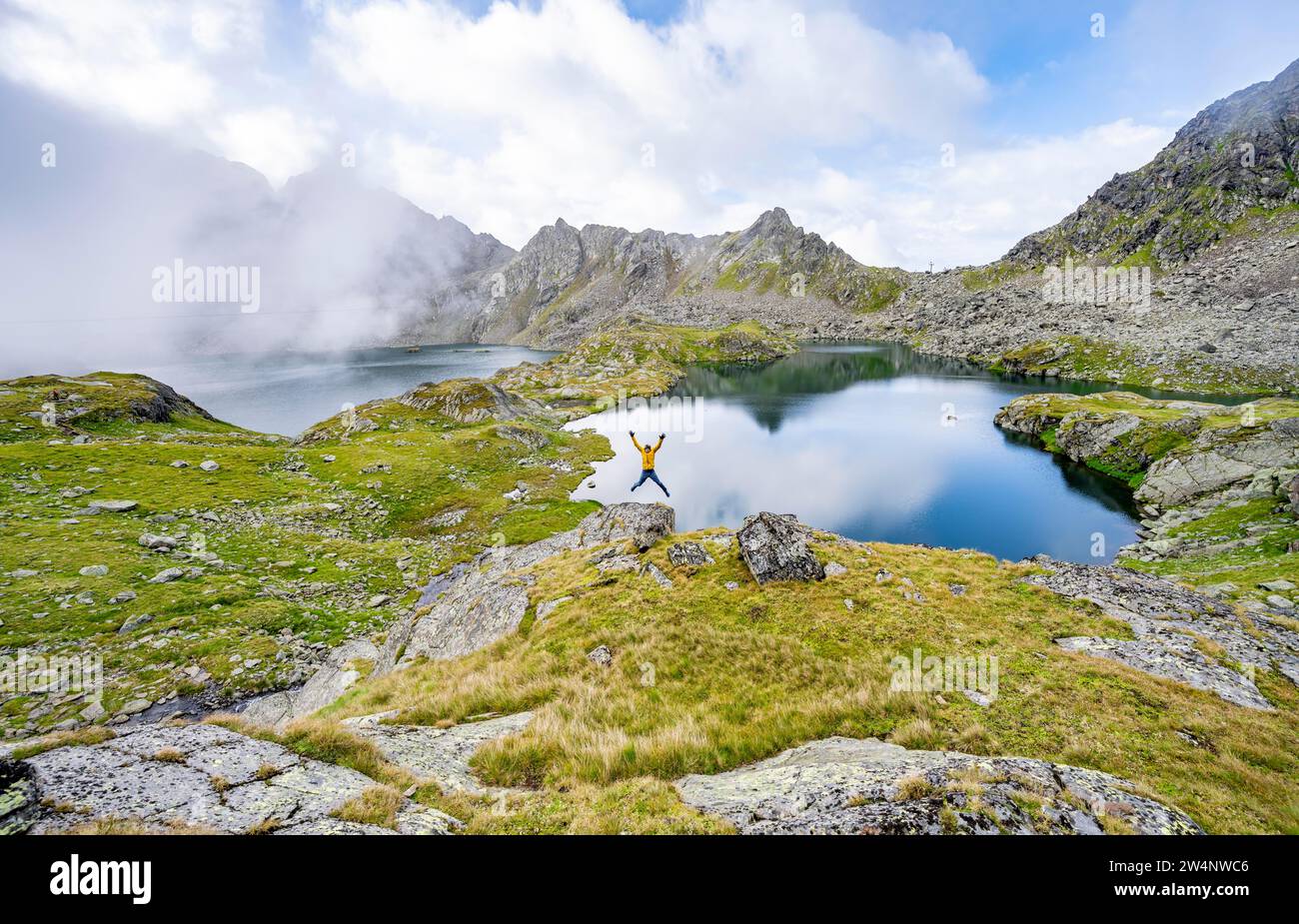 Mountaineer jumping into the air, mountain landscape with lake plateau, Kreuzsee and Wangenitzsee, Wiener Hoehenweg, Schober group, Hohe Tauern Stock Photo