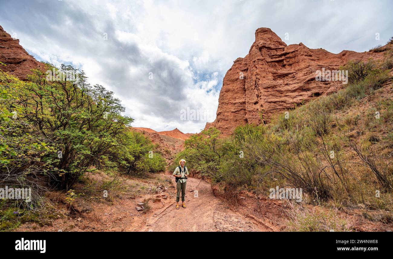Mountaineer in a canyon with a dry stream bed, eroded mountain ...