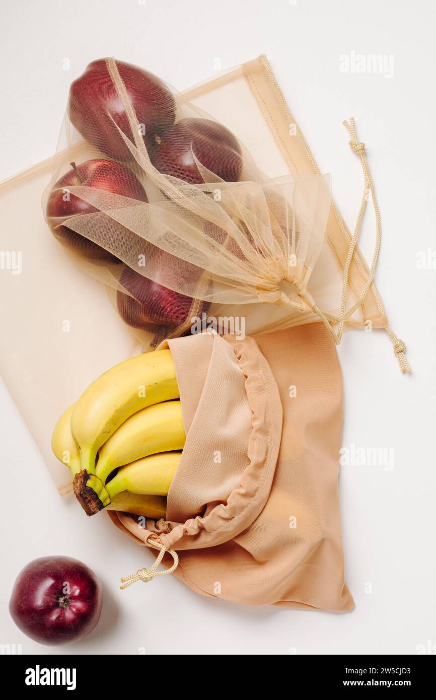 Red apples and bananas in reusable bags. Stock Photo