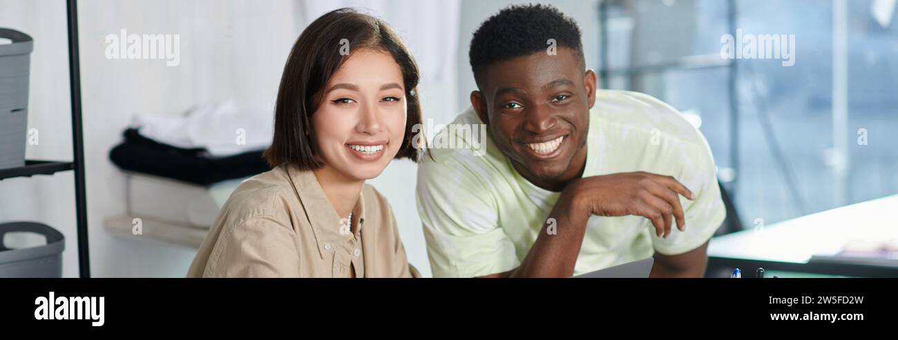 successful multiethnic fashion designers smiling at camera in print studio, horizontal banner Stock Photo