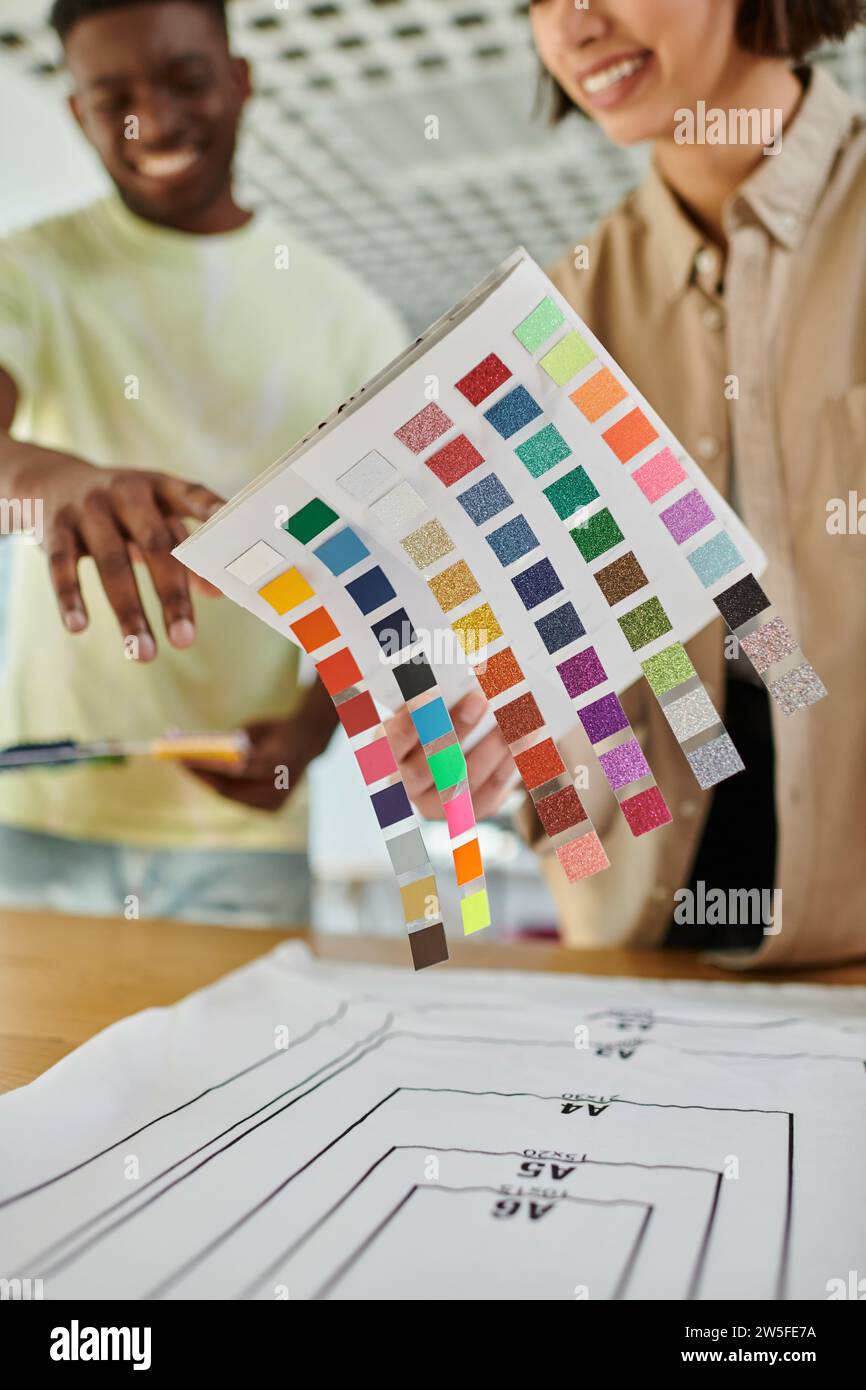 blurred interracial fashion designers holding color palette while working in print studio, teamwork Stock Photo