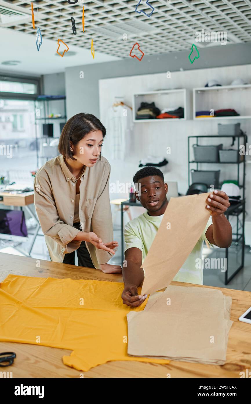 young interracial fashion designers working with sewing patterns in print studio, creativity Stock Photo