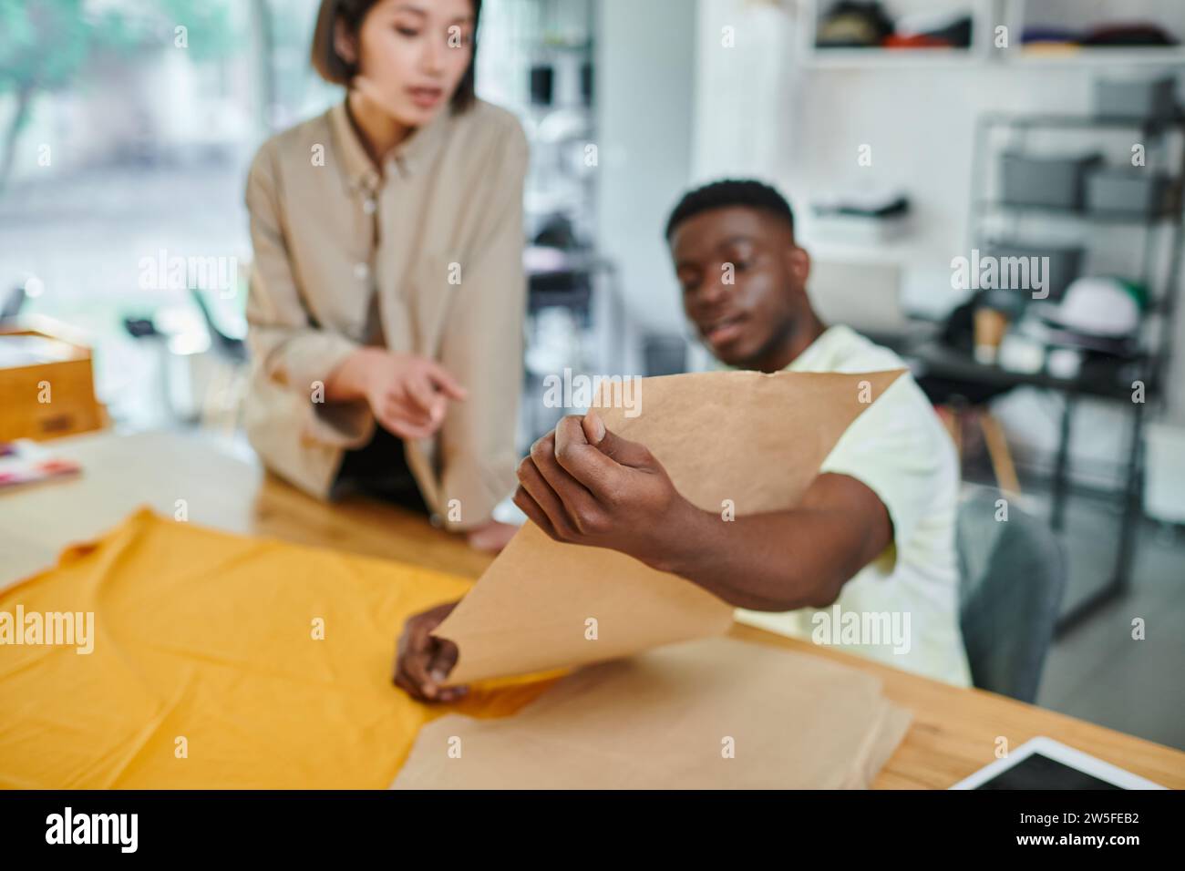 young interracial entrepreneurs working with sewing patterns in print studio, creative manufacturing Stock Photo