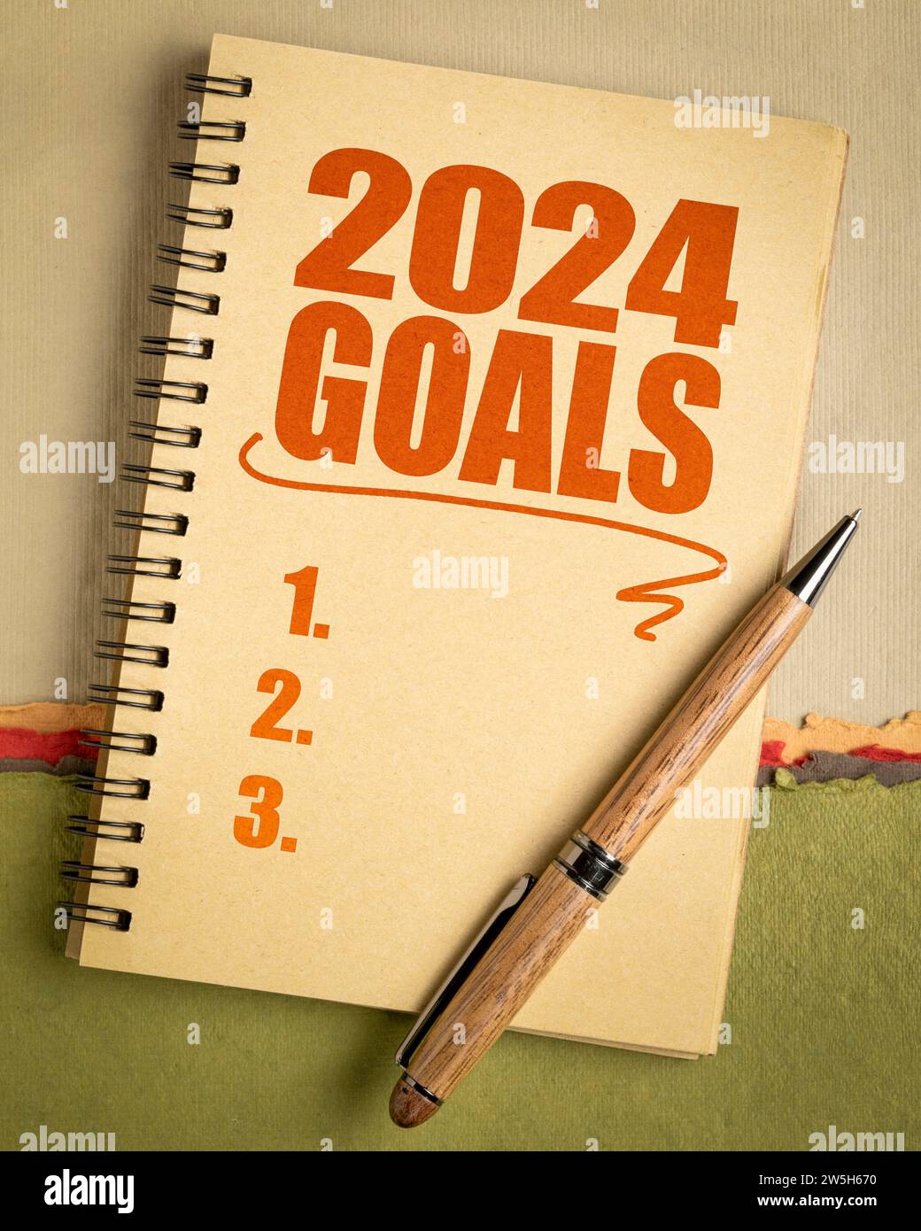 2024 goals list in a notebook with pen, setting New Year goals and