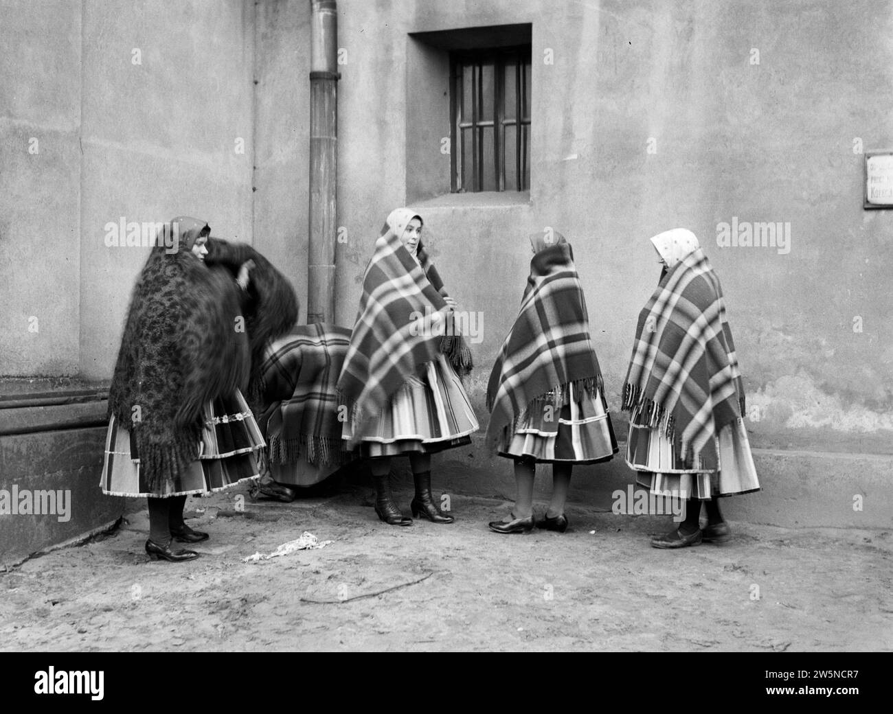 Women in Lowicz wrap their checkered cloths before entering the church ca. 1934 Stock Photo