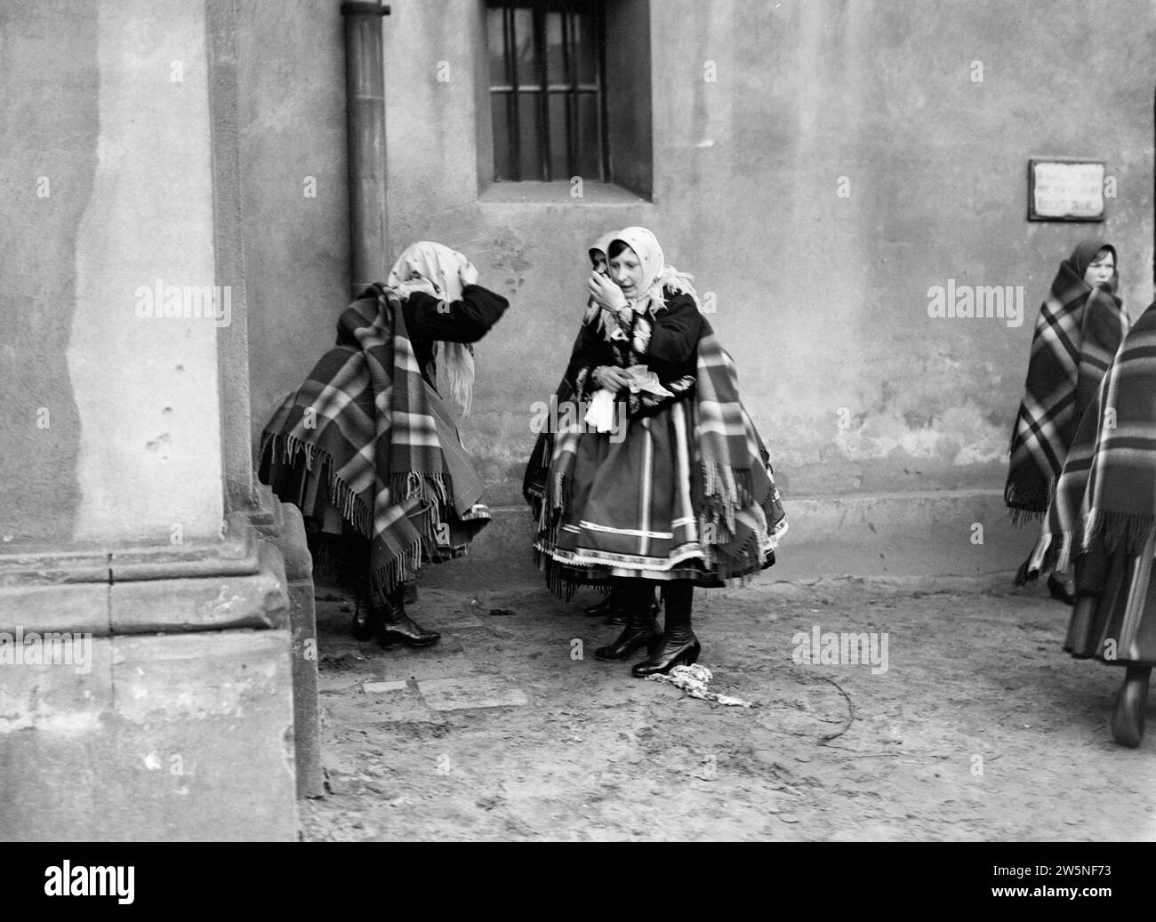 Women in Lowicz check themselves in the mirror before entering the church ca. 1934 Stock Photo