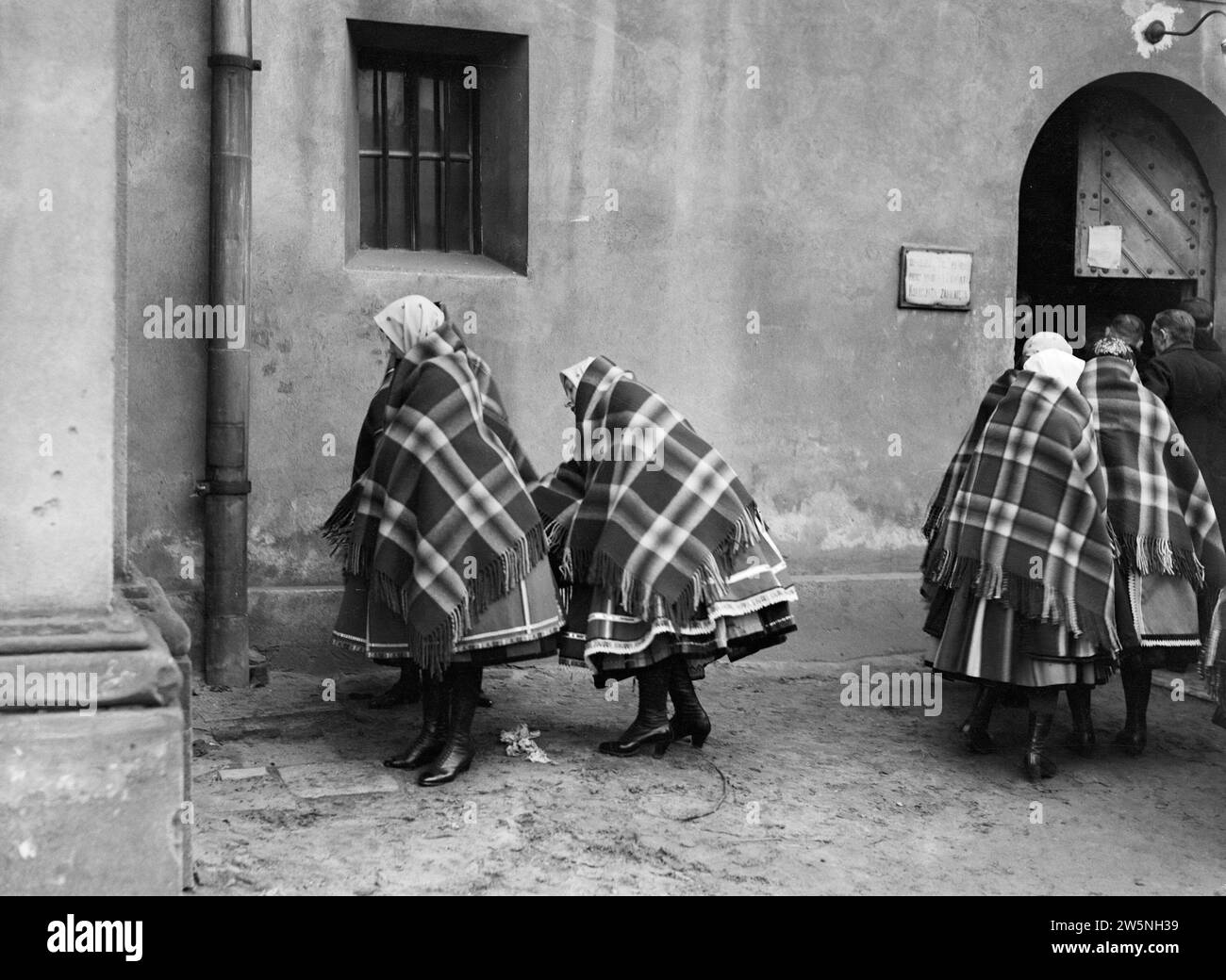 Women in Lowicz put their clothes in order before entering the church ca. 1934 Stock Photo