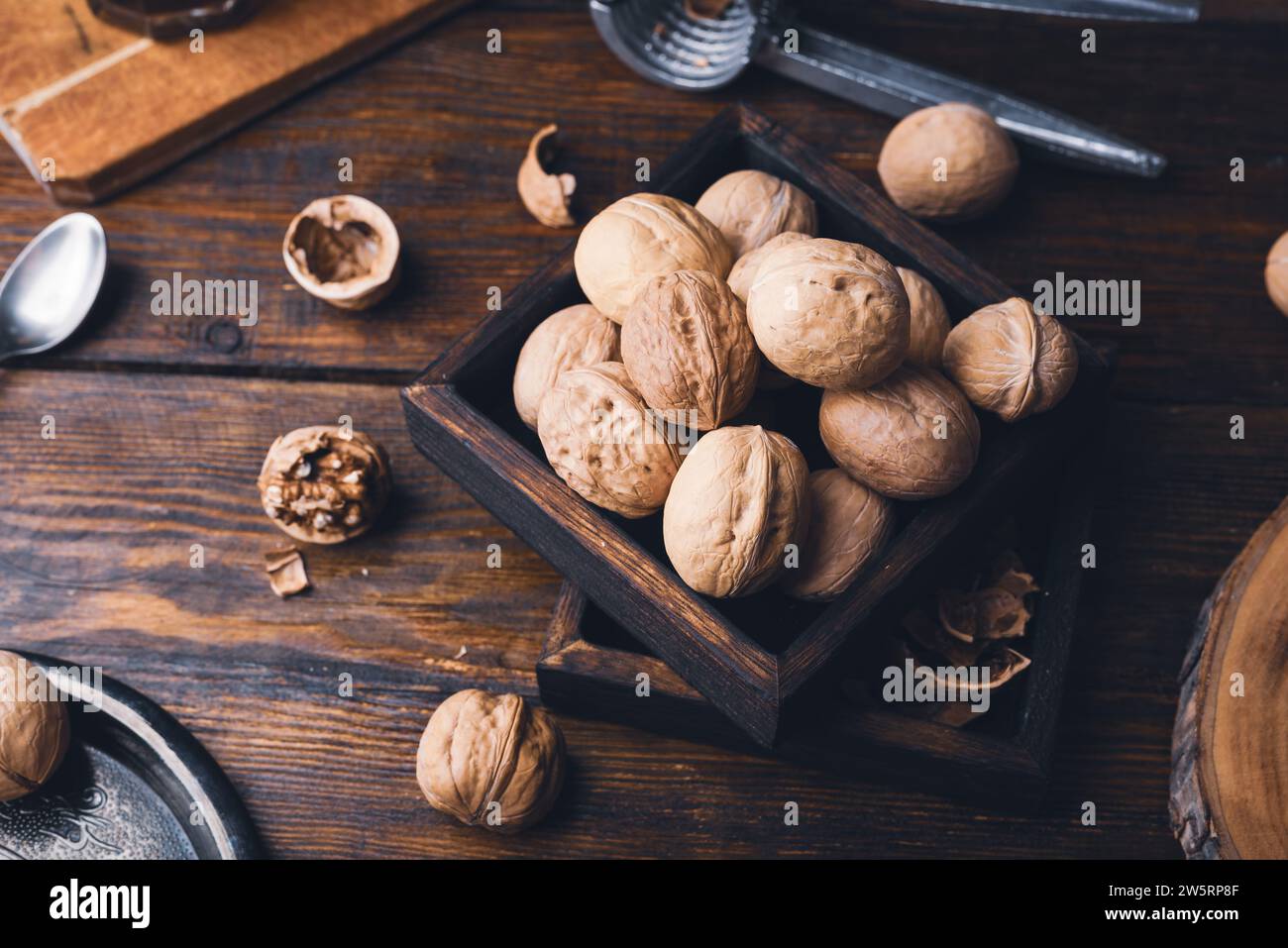 Walnuts in small wooden box and nutcracker on rustic table Stock Photo
