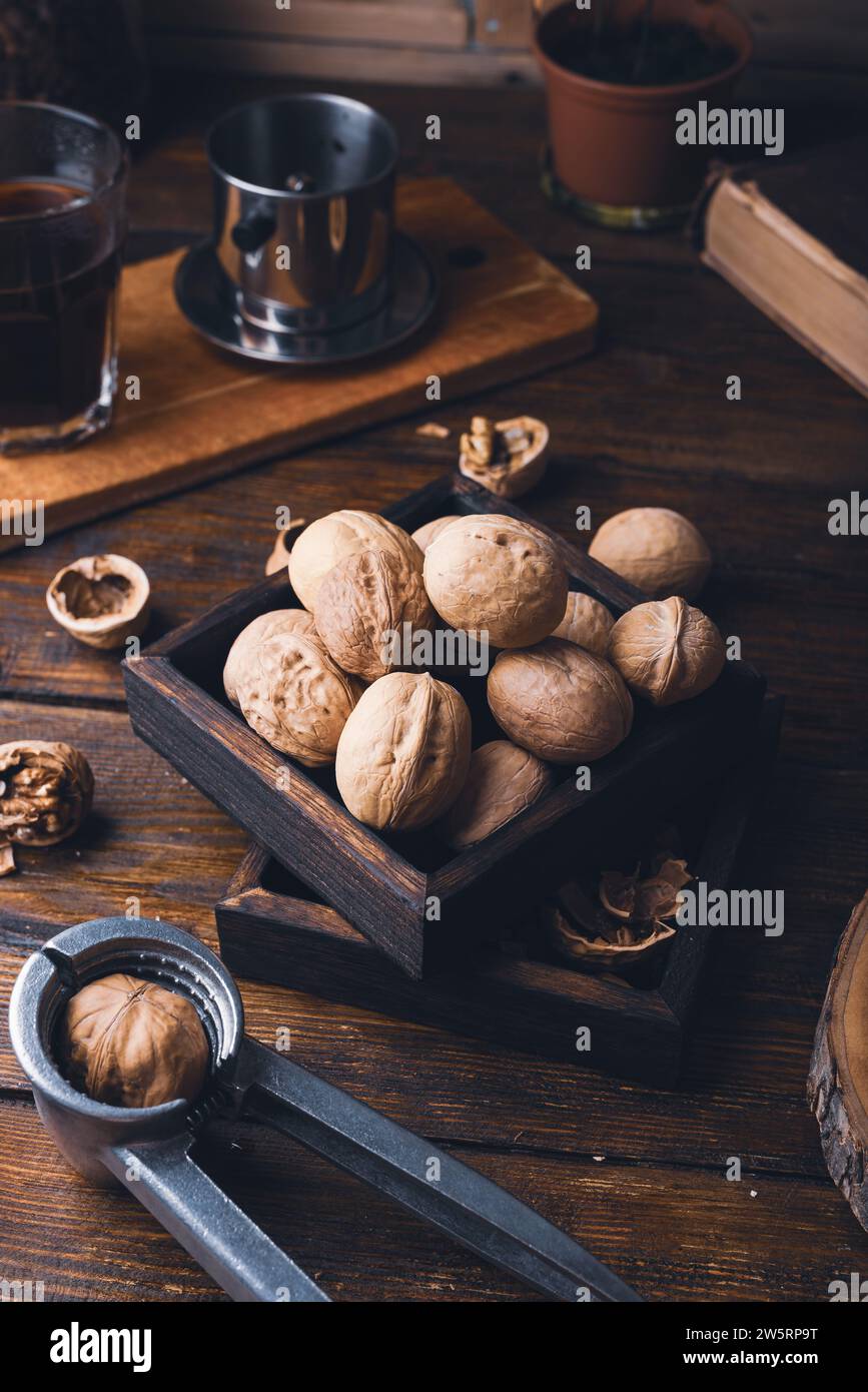 Walnuts in small wooden box and nutcracker on rustic surface Stock Photo