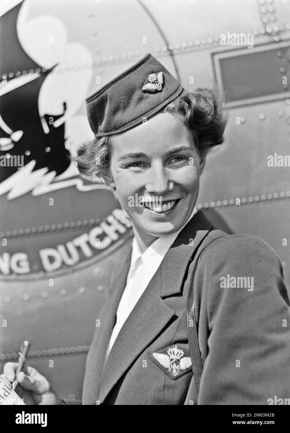 A KLM flight attendant poses in front of an aircraft with the Flying Dutchman emblem ca. August